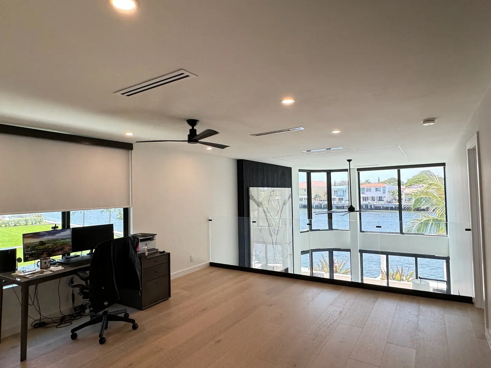 After: Loft office with wide plank flooring and a waterway view